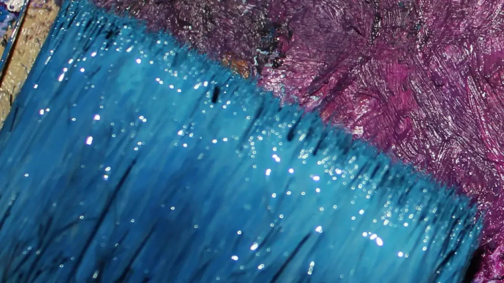 Das Bild zeigt einen breiten Pinsel, der kräftig mit blauer Farbe getränkt ist.